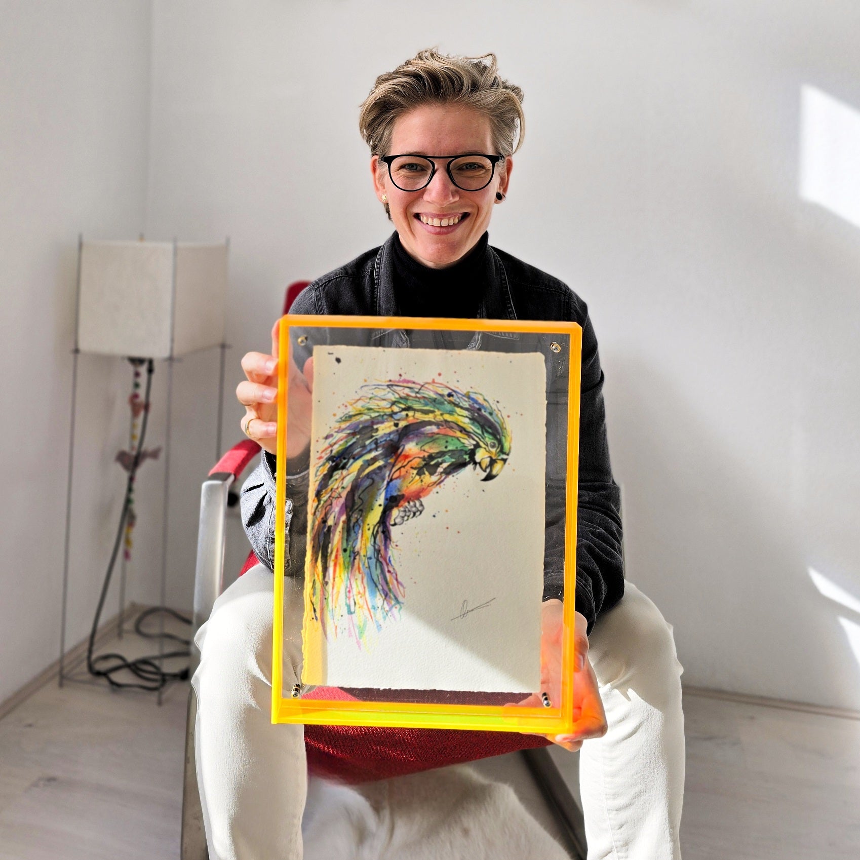 Quirine zit op een stoel en houdt een handgemaakt origineel kunstwerk van een papegaai vast
