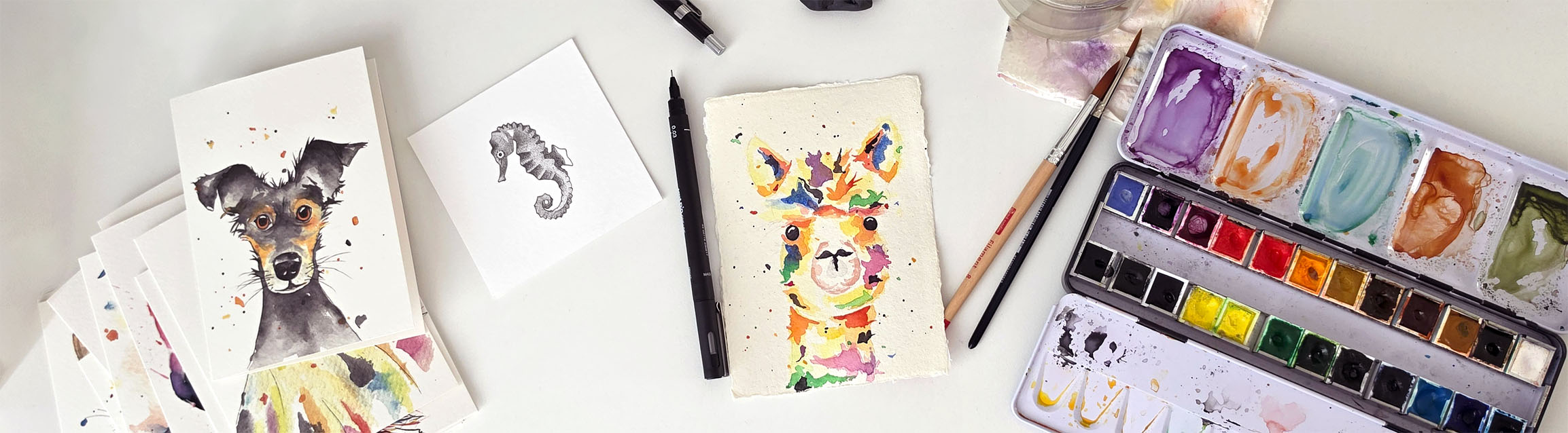 Overzichtsfoto van bureau met teken- en schildermaterialen, originele kunstwerken en dierenkaarten