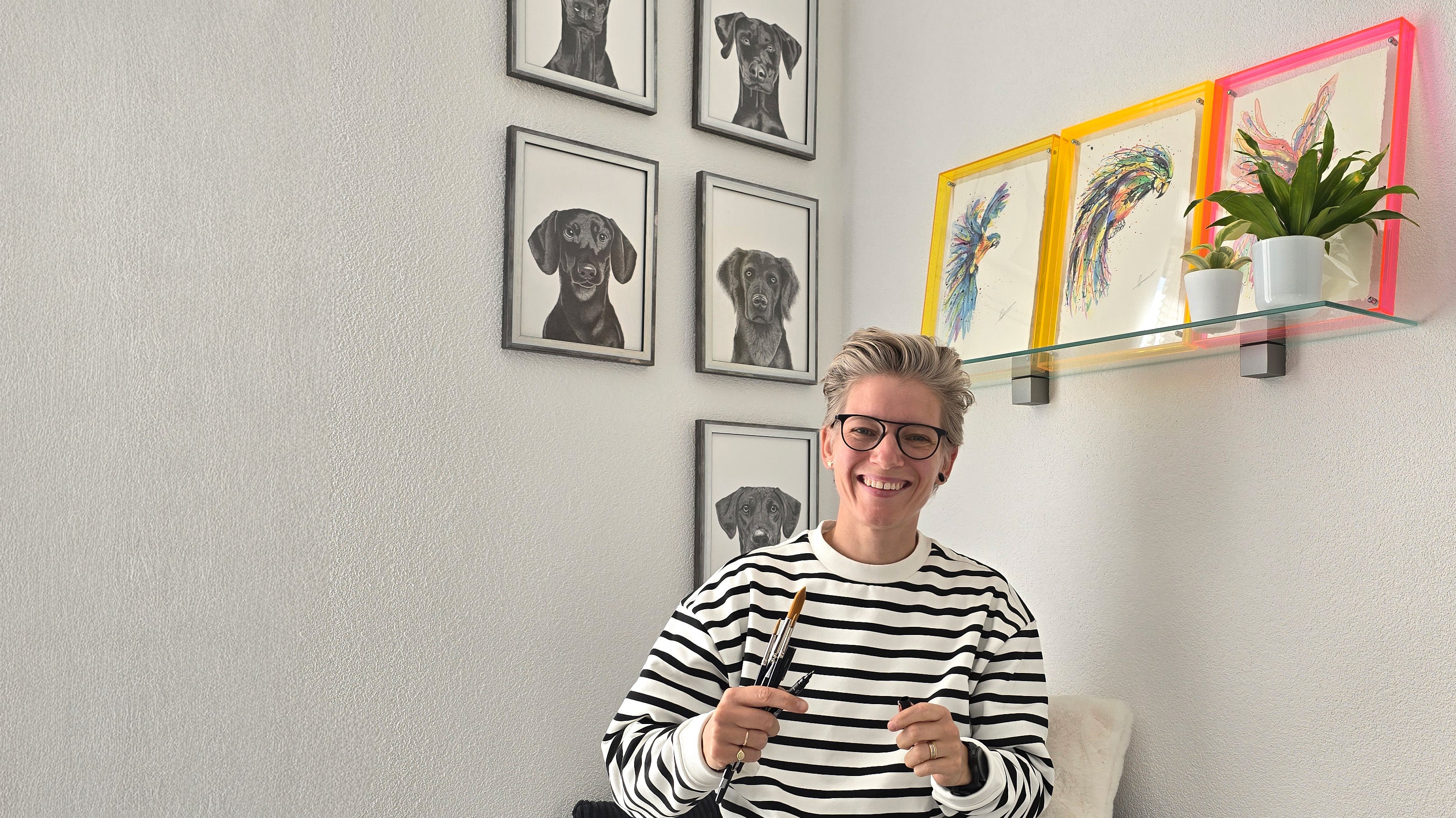 Quirine in atelier met handgetekend en handgeschilderde kunstwerken aan de muur