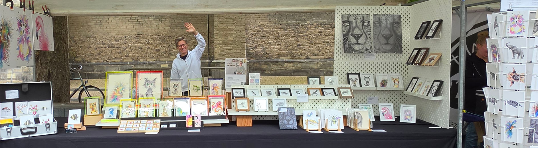 Quirine zwaait naar camera vanachter de marktkraam